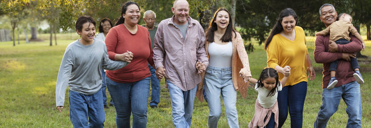 Multiracial extended family run playfully holding hands